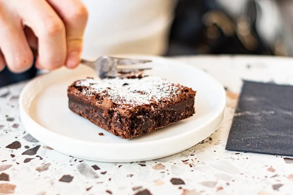 Bolo ou brownie? Qual é a diferença entre as duas receitas 3 pessoa cortando um pedaço de brownie de chocolate. Bolo ow brownie