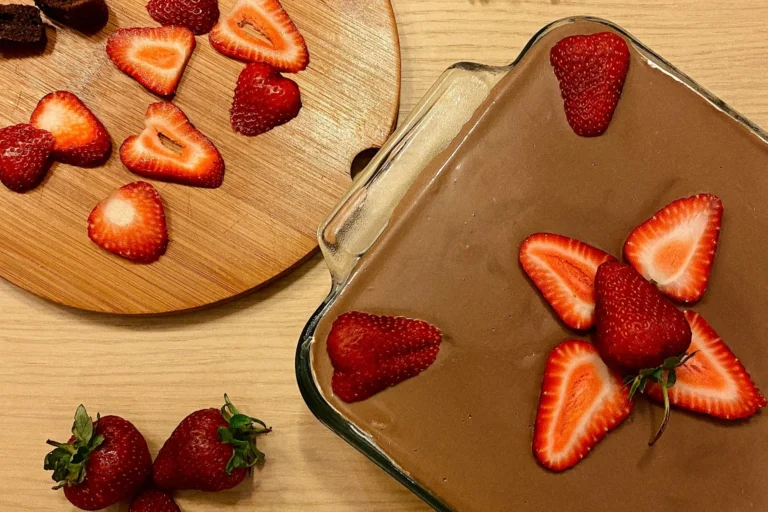 sobremesas de chocolate para o natal 2025. Sobremesa coberta com chocolate e morango em pedaços sobre uma mesa de madeira.